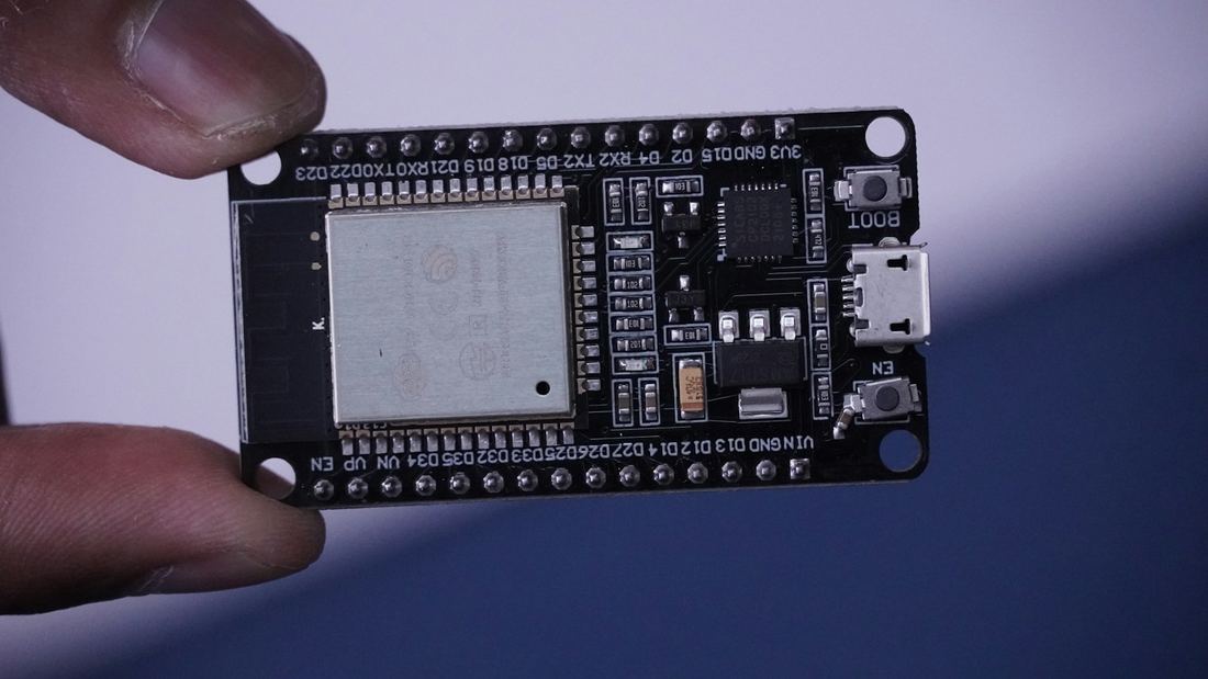 ESP32 development board held between the fingers