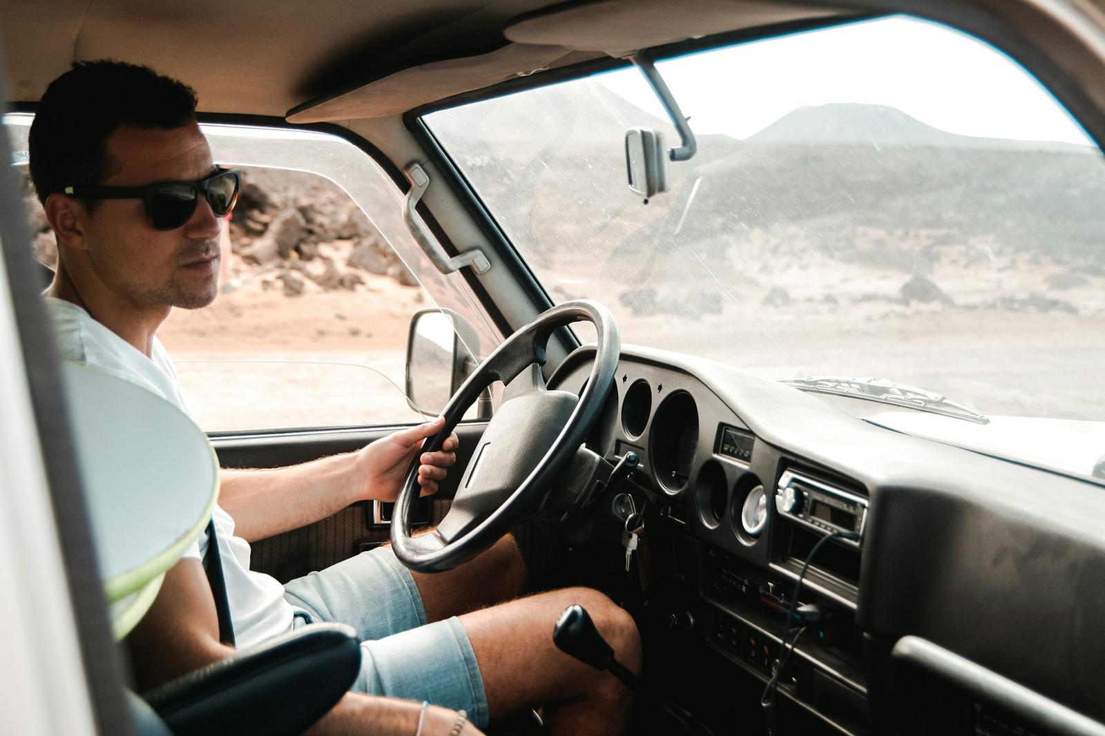 Driver wearing sunglasses at the wheel, seen from inside the cab